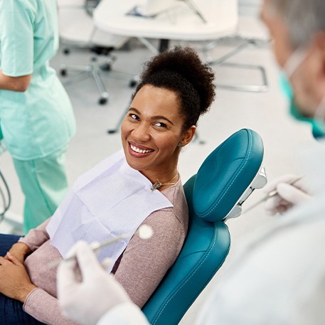 Woman smiling at dentist while sitting in treatment chair