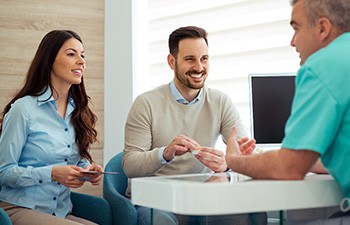 Dentist and couple talking in dental office