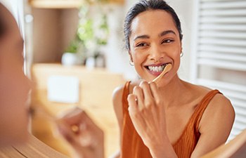 Woman smiling while brushing her teeth