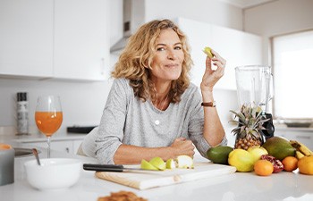 Woman smiling while eating healthy snack in kitchen