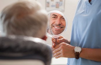 Patient smiling at reflection in handheld mirror