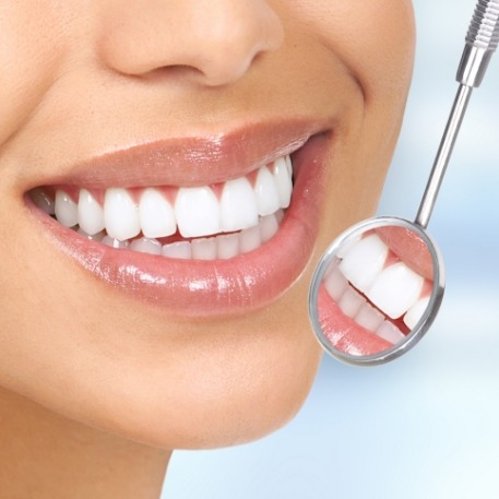 Dental mirror next to smile with straight white teeth