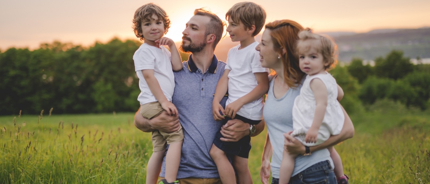 Family of five smiling outdoors at sunset after dental services in Califon