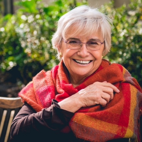 Senior woman smiling and wearing shawl outdoors