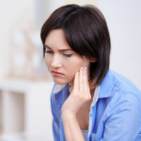 Woman holding the side of her jaw in pain