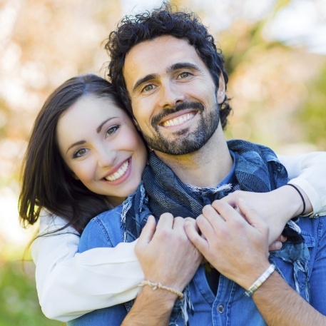 Smiling man and woman embracing outdoors