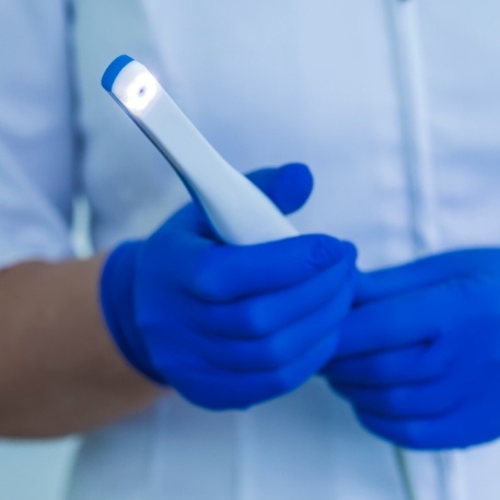 Dental professional holding a thin white intraoral camera