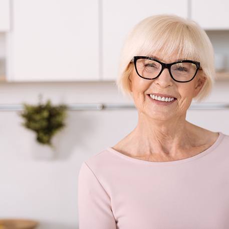 Senior woman standing and smiling in  her kitchen