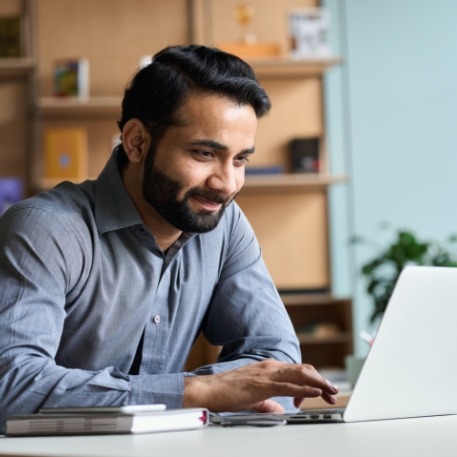 Man smiling while using laptop at desk