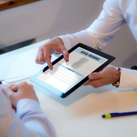 Two people looking at dental insurance forms on a tablet