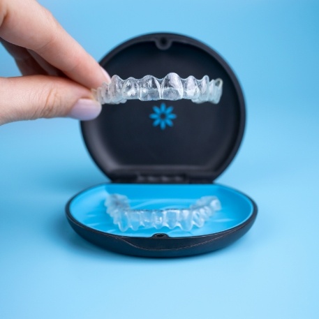 Person placing an Invisalign aligner in Califon back in its storage case