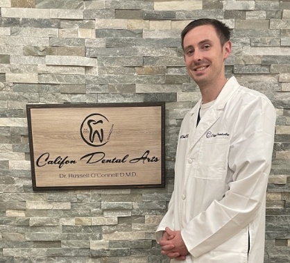 Califon New Jersey dentist Doctor Russell O Connell standing next to wooden sign for Califon Dental Arts