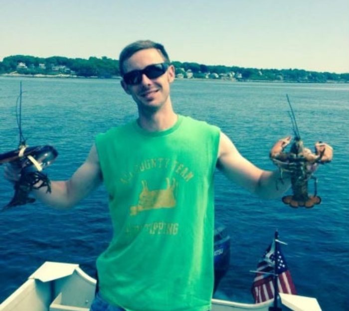 Doctor O Connell on a boat holding two freshly caught lobsters