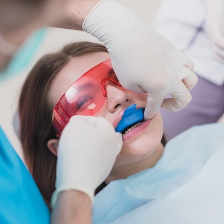 Young woman in dental chair with fluoride trays on her teeth