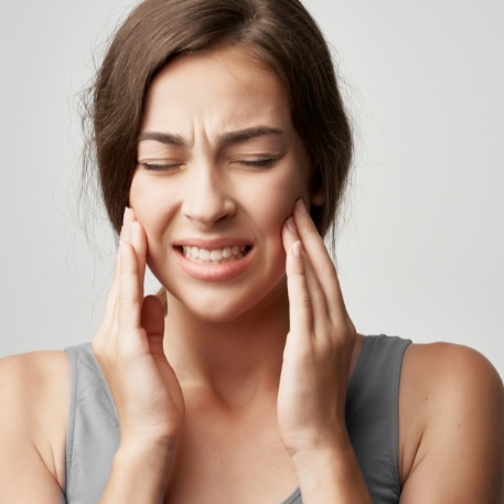 Woman holding her jaw joints in pain before T M J treatment in Califon