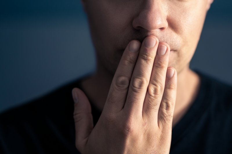 A shy man covering his mouth with his hand