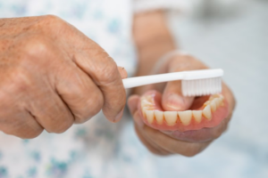 Close up of someone’s hands as they brush their denture