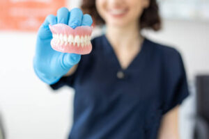 Lab technician holding set of dentures 